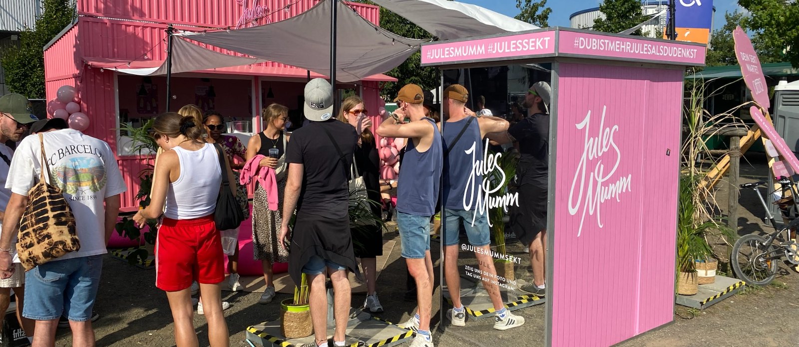 Gäste warten vor einer vollflächig im Kundendesign gestalteten Fotobox von Flash-U auf einem Sommerevent