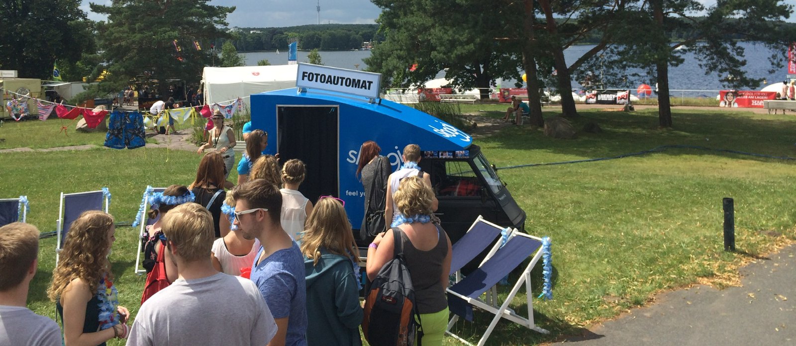Gäste warten vor dem Fotomobil von Flash-U mit Dachschild Fotoautomat auf einem Sommerevent