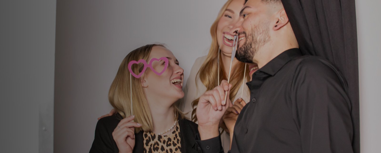 Gäste lachen mit Requisiten vor der Fotobox von Flash-U in der Auermühle in Ratingen
