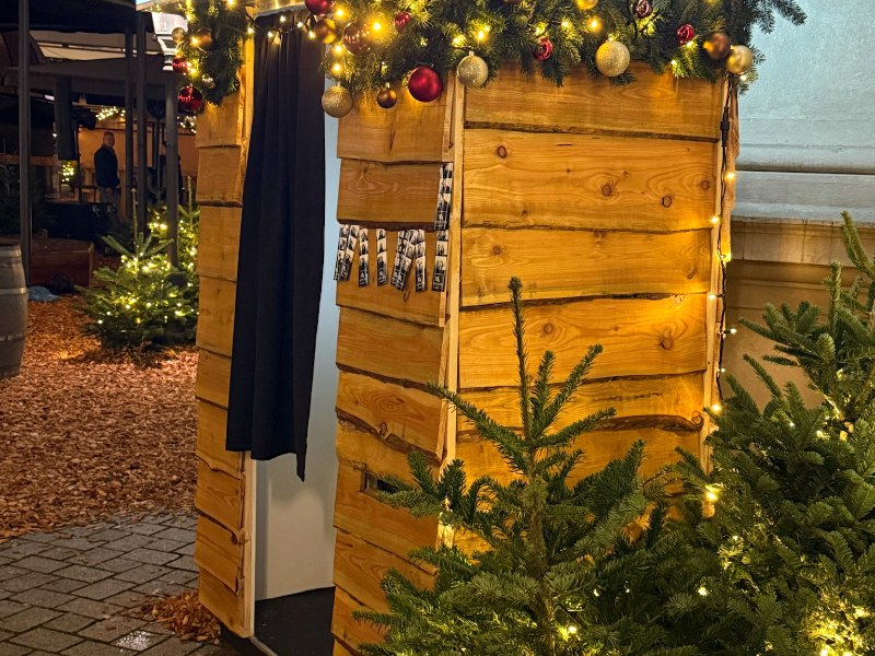 Fotokabine im Holzlook, weihnachtlich mit Tannengrün, Christbaumkugeln und Lichterketten dekoriert