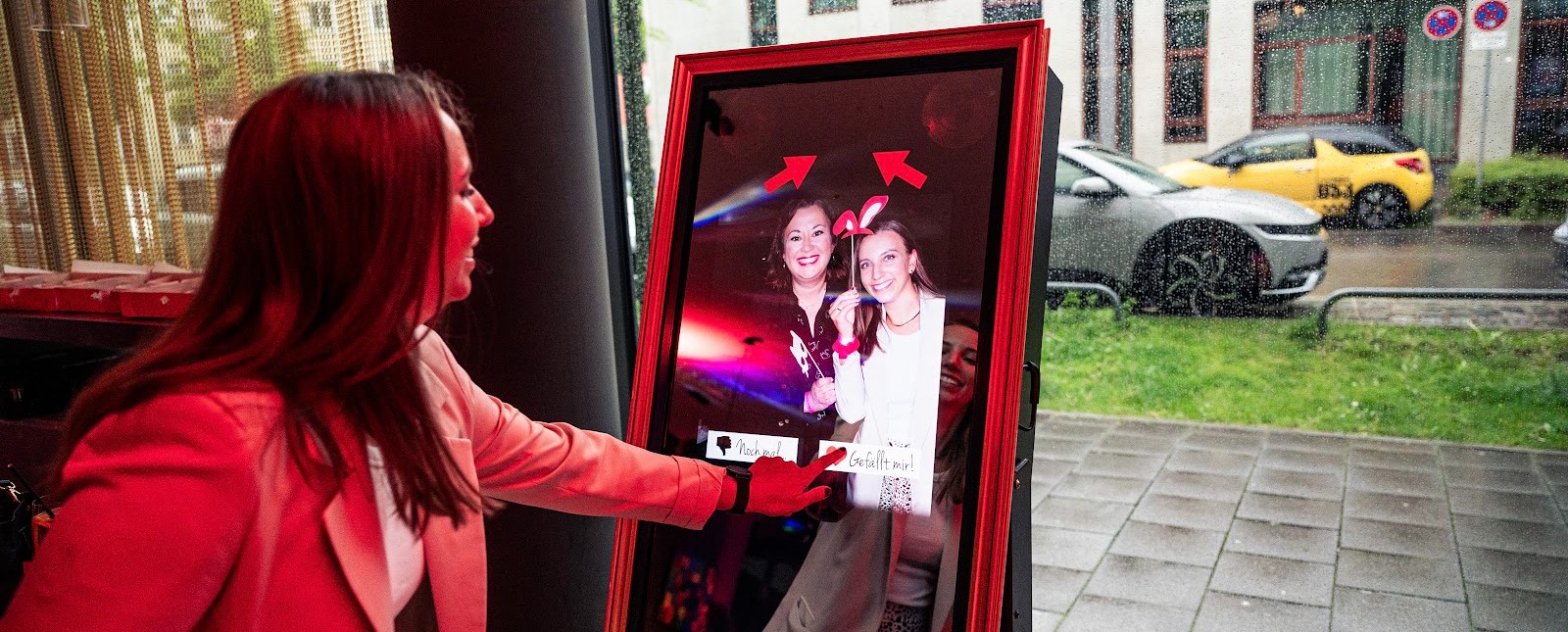 Gast tippt am Fotospiegel von Flash-U auf „Gefällt mir“ — zwei lachende Kolleginnen auf dem Bildschirm